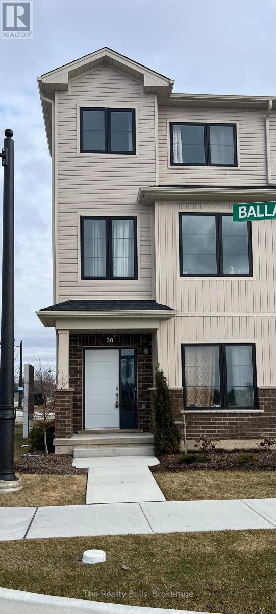 A two-story beige house with a white door and a green street sign that says "BALL".