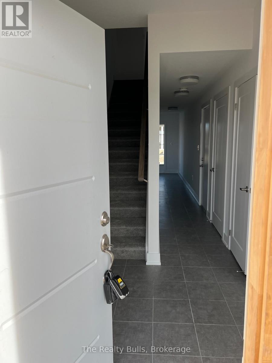 A hallway with a white door and a black staircase.