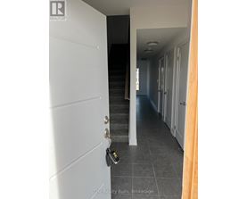A hallway with a white door and a black staircase.