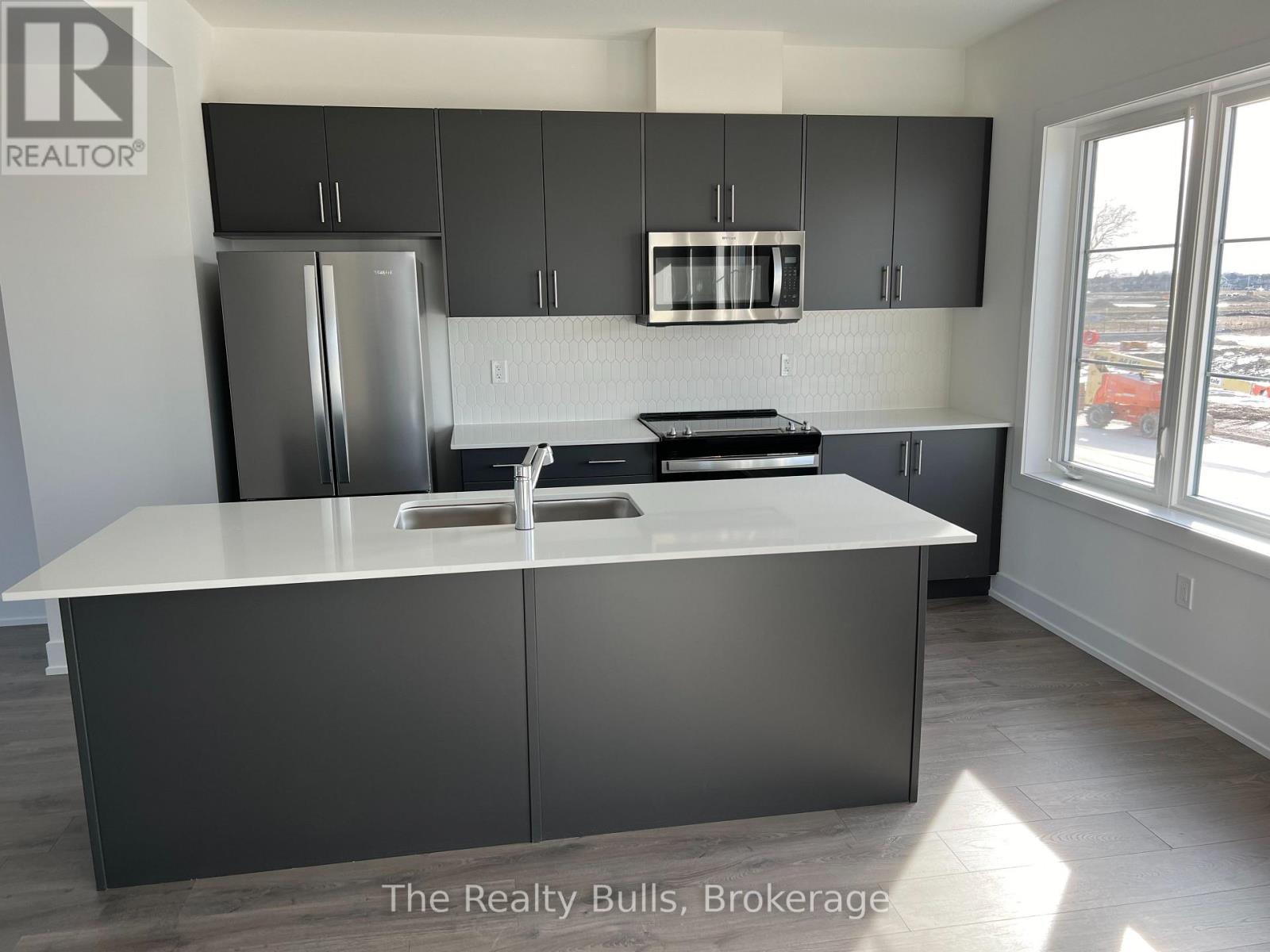 A kitchen with a white counter top and grey cabinets.
