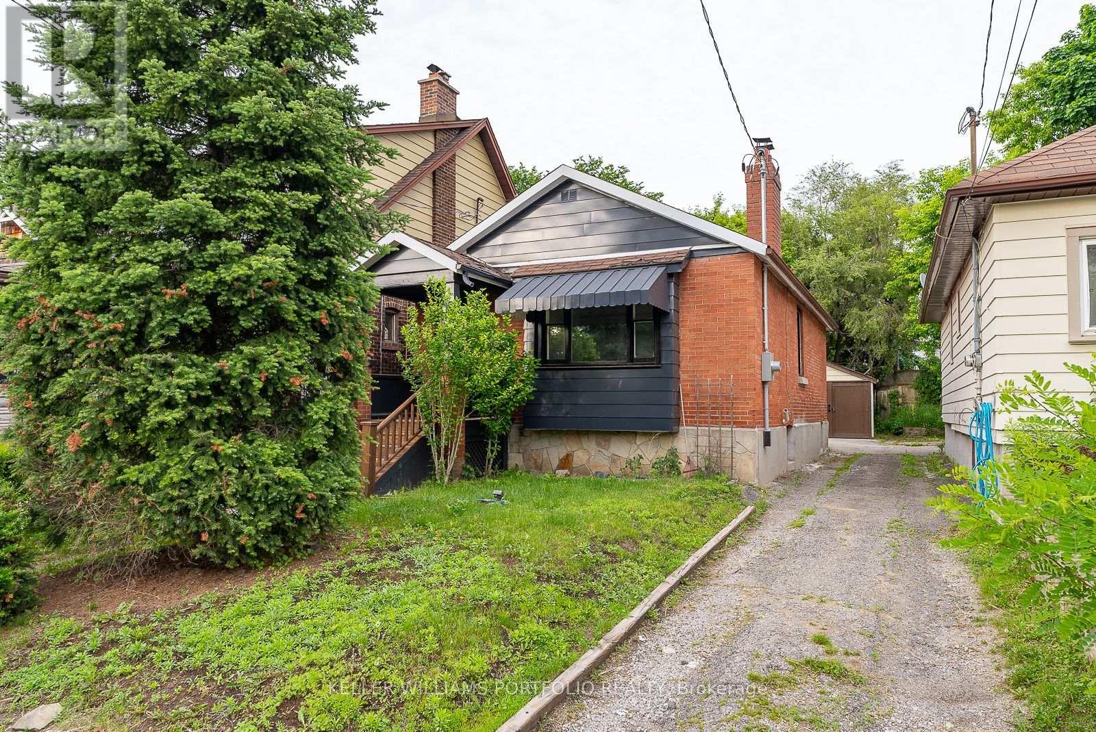 A gravel path leads to a house with a brick chimney.