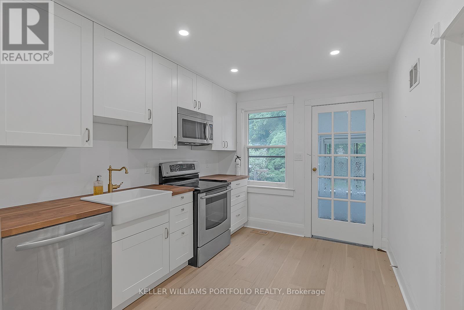A kitchen with white cabinets and a wooden counter top.