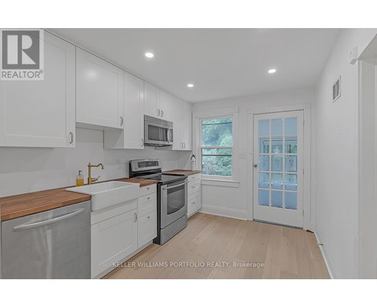 A kitchen with white cabinets and a wooden counter top.