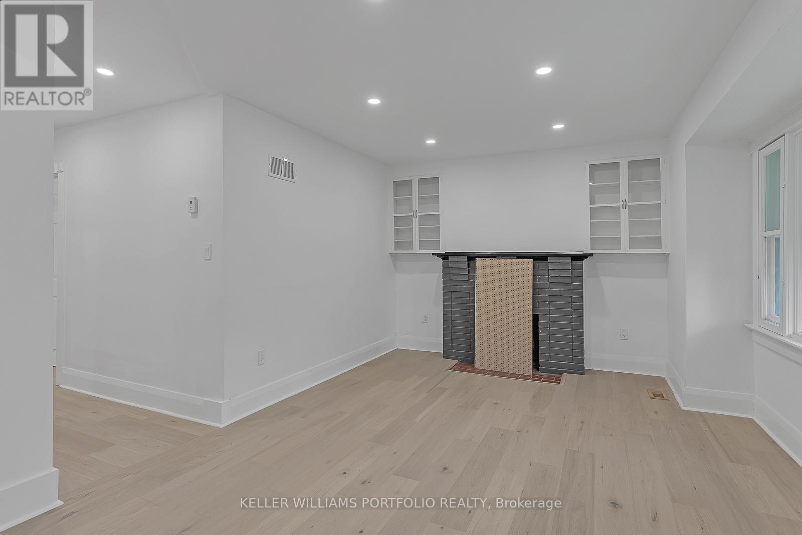 A spacious room with wooden flooring and white walls.