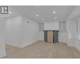 A spacious room with wooden flooring and white walls.