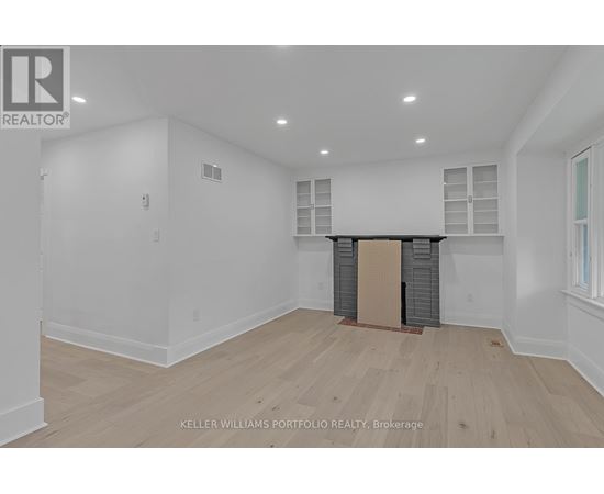 A spacious room with wooden flooring and white walls.