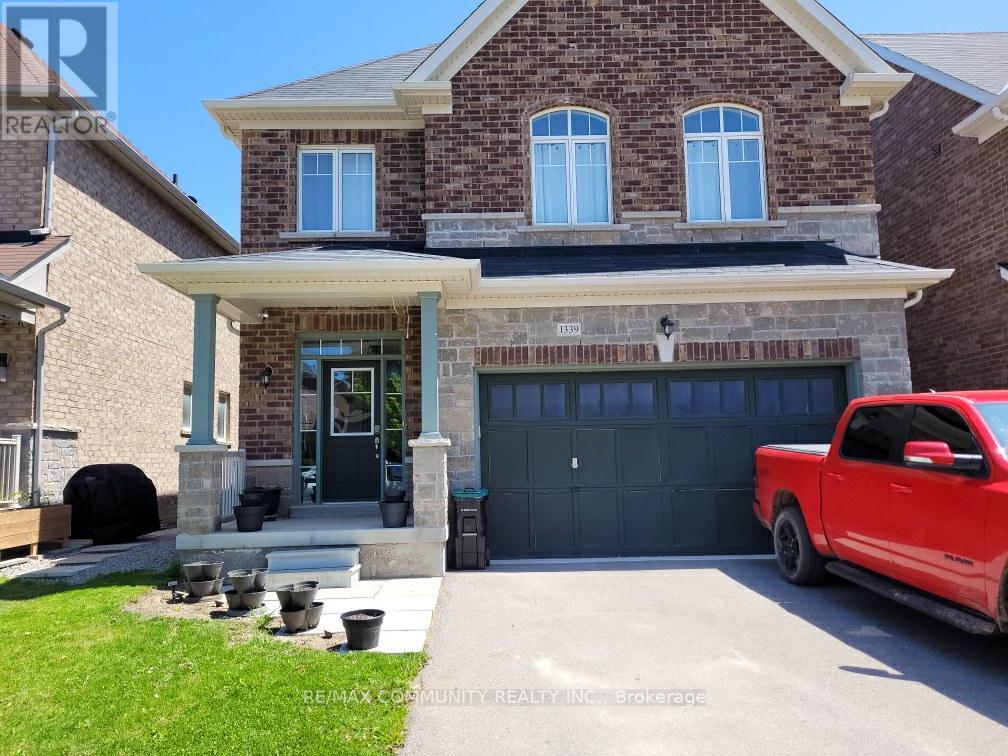 A red pickup truck is parked in front of a two-story house with a garage.