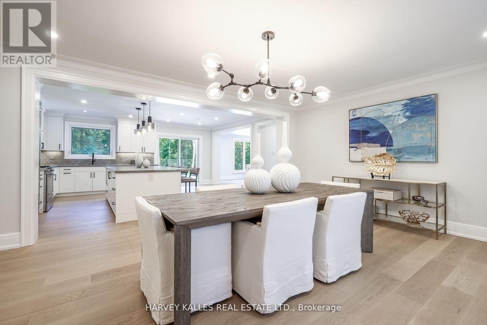 A well-lit dining room with a wooden table and white chairs.