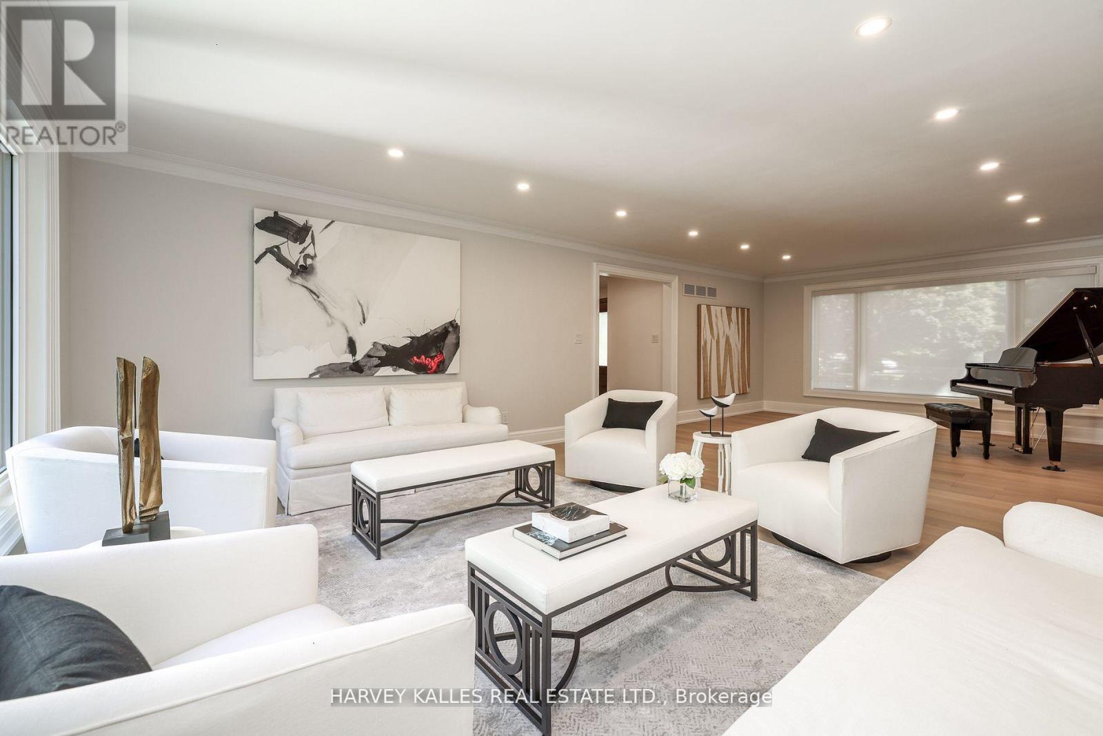 A living room with white furniture and a piano.