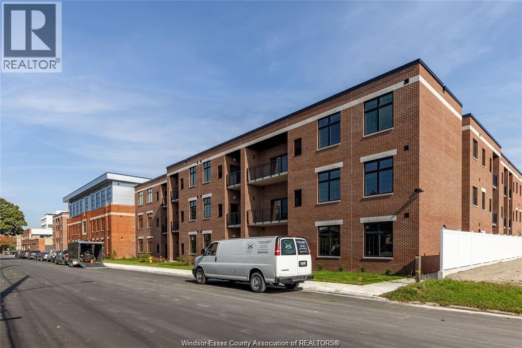 A white van is parked on the side of a street in front of a brick building.