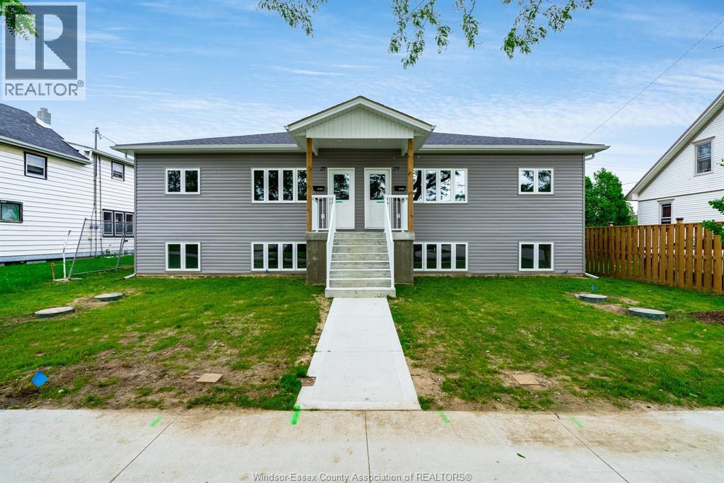 A house with a grey facade and a white door is for sale.