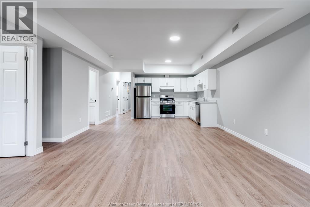 A spacious kitchen with white cabinets and a wooden floor.