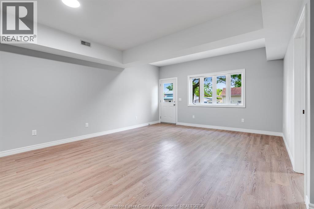 A spacious room with wooden flooring and a large window.