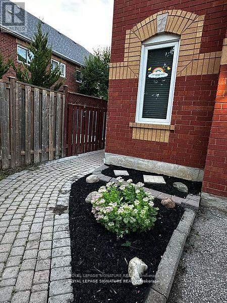 A small garden with a flower bed in front of a red brick wall with a window.