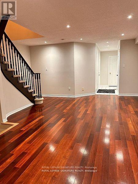 A spacious room with wooden flooring and a staircase.