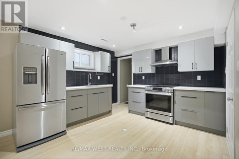 A modern kitchen with a stainless steel refrigerator and wooden flooring.