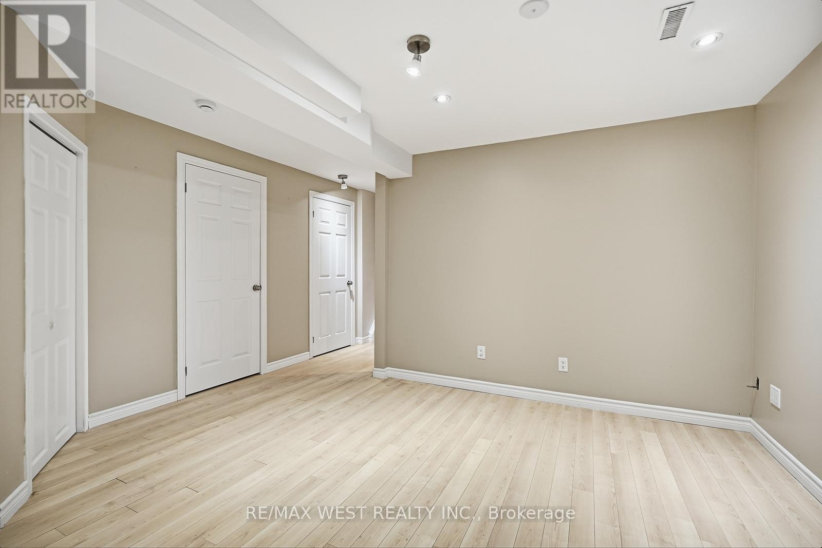 A spacious room with wooden flooring and white doors.