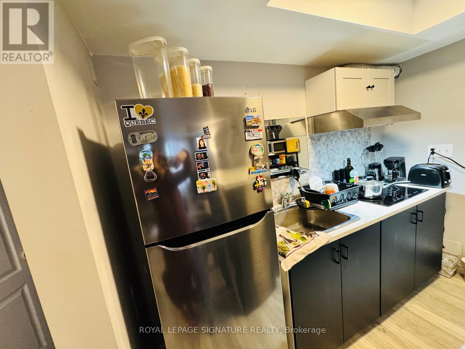 A kitchen with a stainless steel refrigerator and black cabinets.