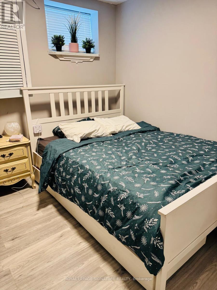 A bedroom with a bed, nightstand, and window.