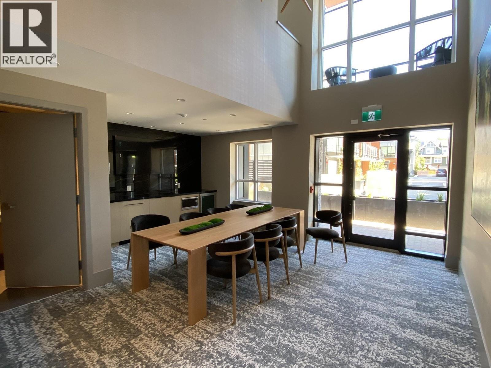 A conference room with a long table and chairs, and a view of the outside through the glass doors.