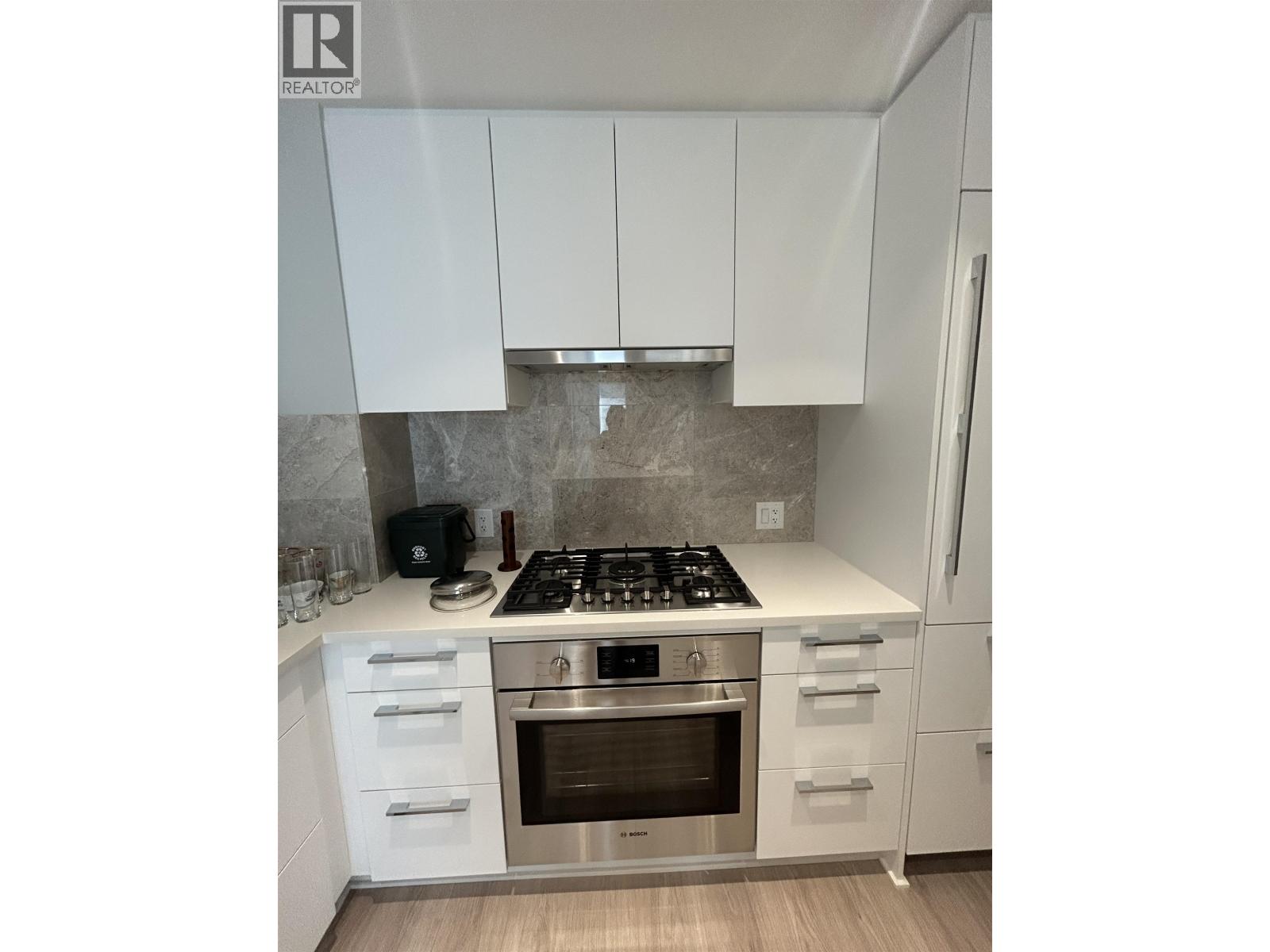 A modern kitchen with white cabinets and stainless steel appliances.