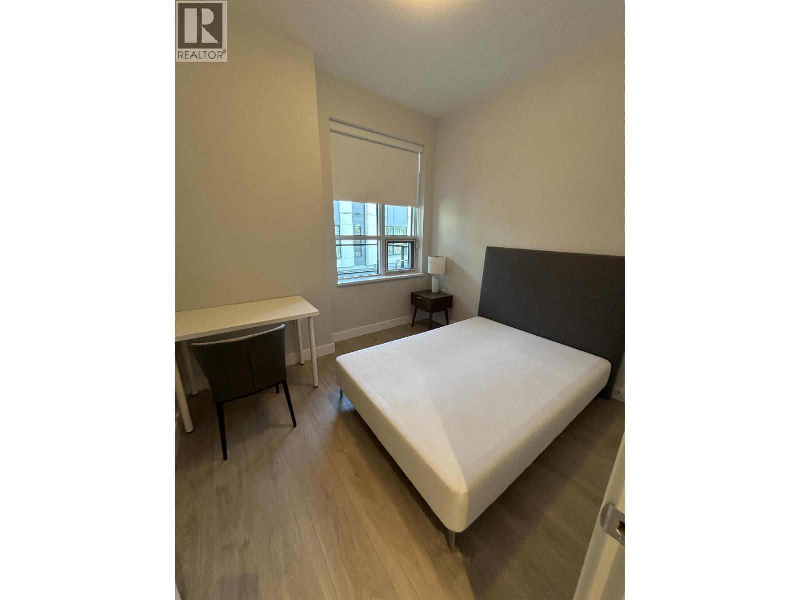 A bedroom with a bed, desk, and chair.