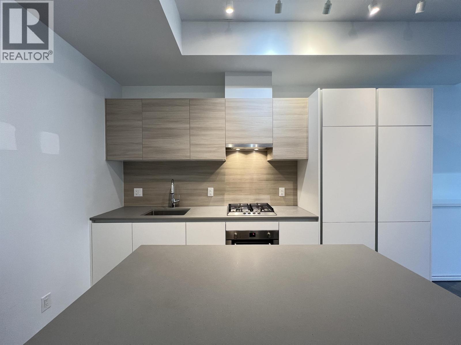 A modern kitchen with a large island and a stove top oven.