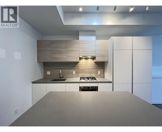 A modern kitchen with a large island and a stove top oven.