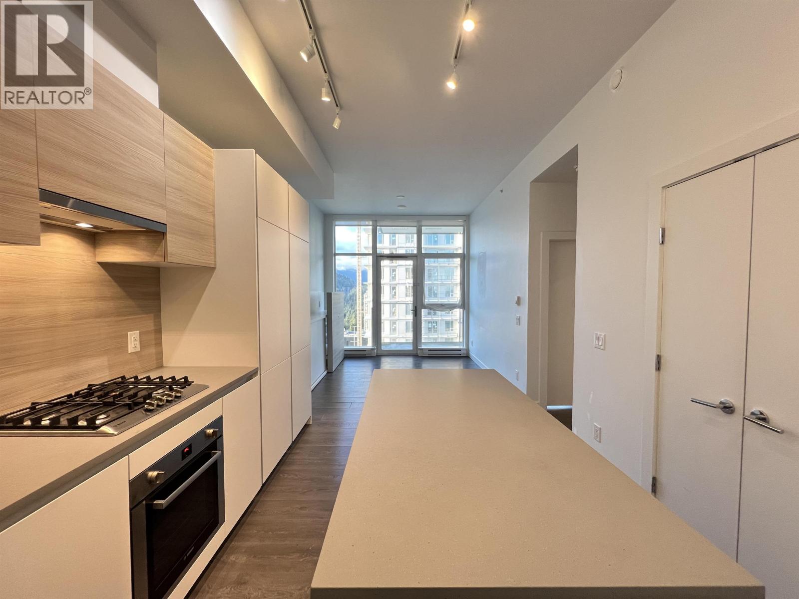 A modern kitchen with a stove top oven and a long counter top.