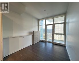 A spacious room with wooden floors and large windows overlooking a cityscape.