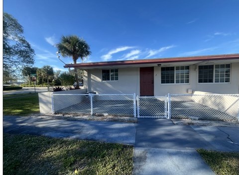 A small building with a red roof and a white fence in front.