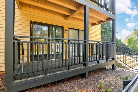 A balcony with a black railing and a wooden floor.
