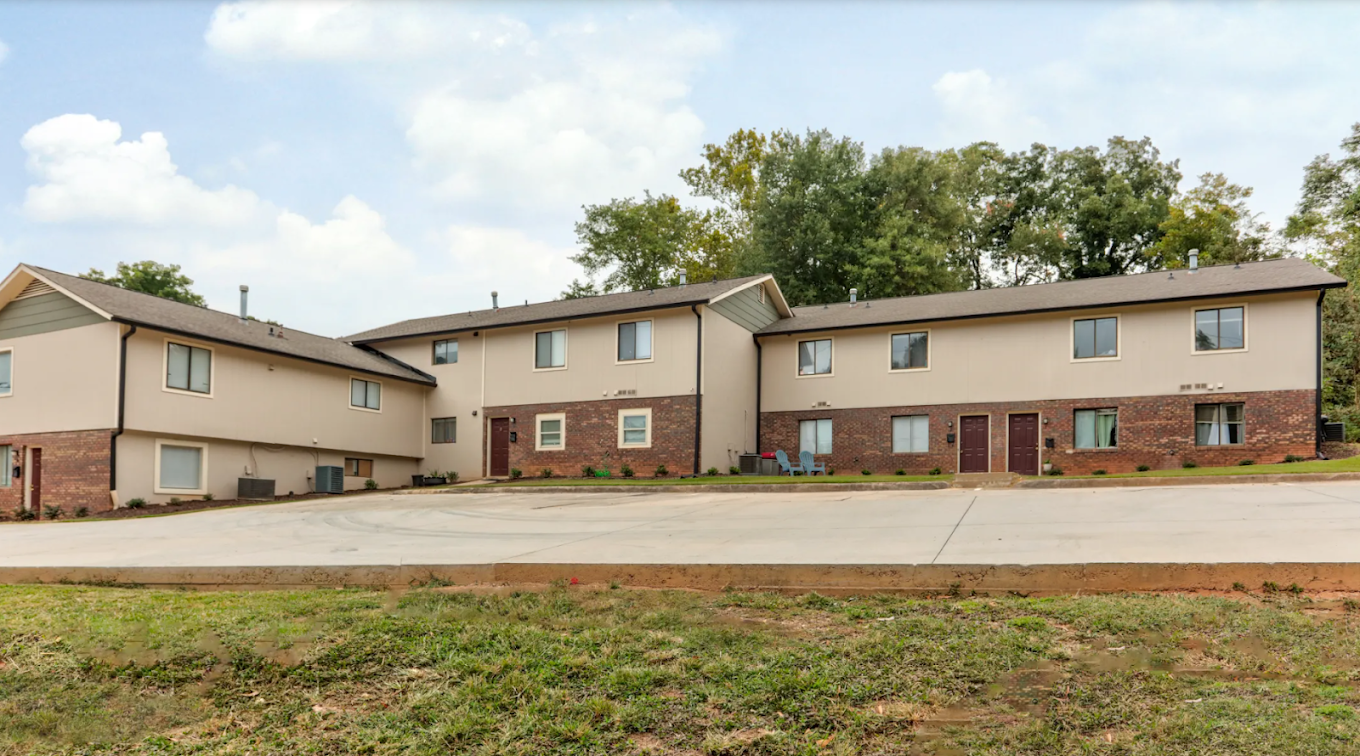 Apartment complex with a parking lot in front.