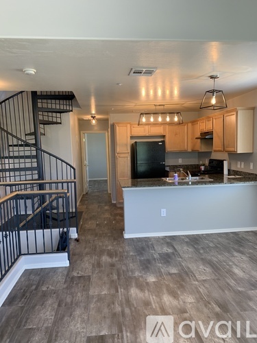 A modern kitchen with wooden cabinets and a TV above the island.