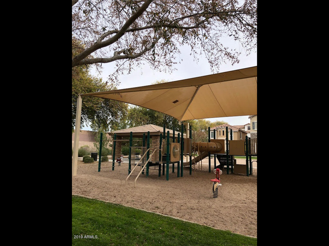 A playground with a yellow canopy and a red slide.