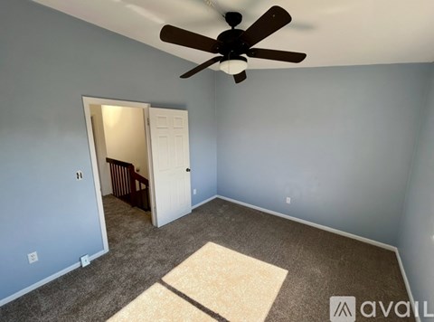 A room with a ceiling fan and a rug on the floor.