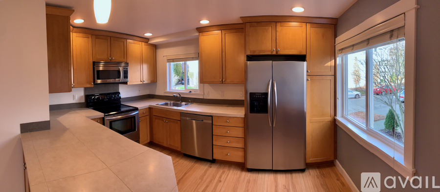 A kitchen with wooden cabinets and a stainless steel refrigerator.