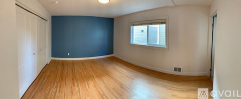 A room with wooden floors and a window with blinds.