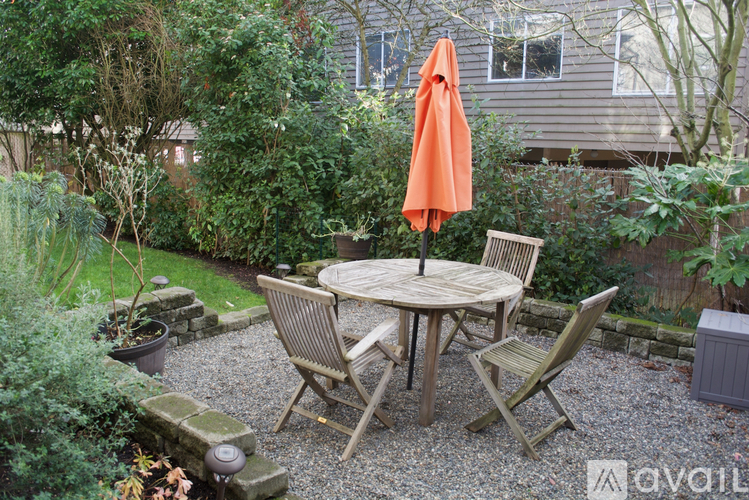 A patio with a table and chairs and an orange umbrella.