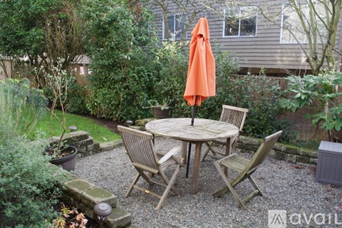 A patio with a table and chairs and an orange umbrella.