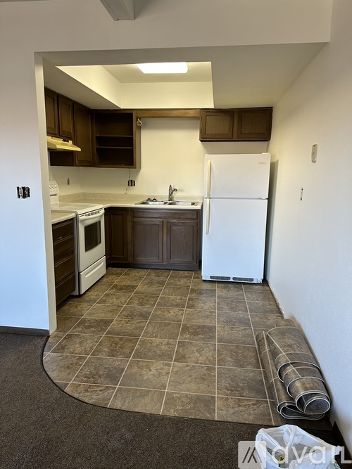 A kitchen with a white fridge and brown cabinets.
