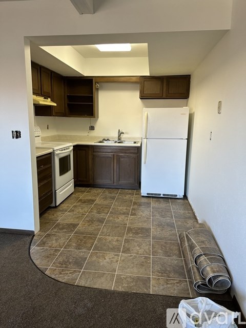 A kitchen with a white fridge and brown cabinets.