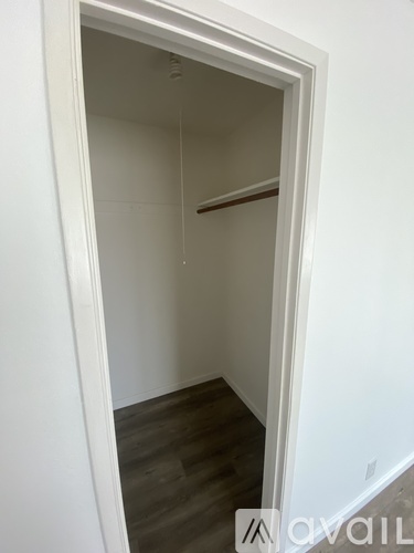 A white doorway leads to a room with a wooden floor.