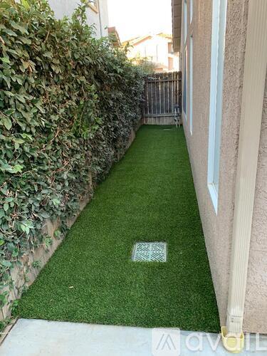 A narrow garden path with artificial grass.