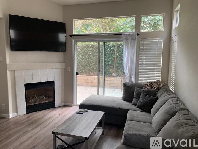A living room with a grey couch and a fireplace.