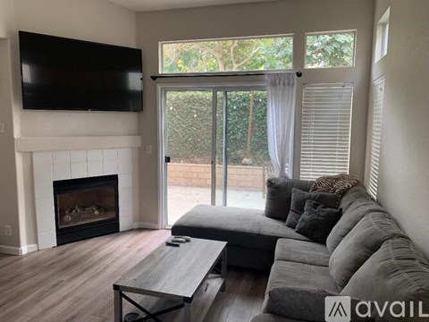 A living room with a grey couch and a fireplace.