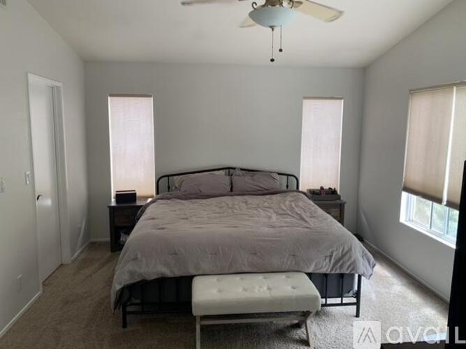 A bedroom with a bed, nightstands, and a window with blinds.