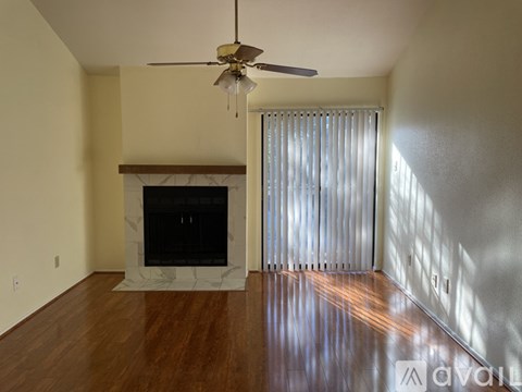 A living room with a fireplace and a ceiling fan.