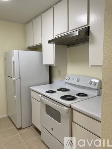 A kitchen with a white stove top oven and a white refrigerator.