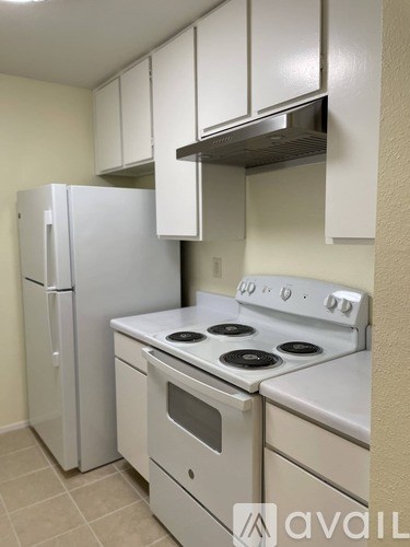 A kitchen with a white stove top oven and a white refrigerator.